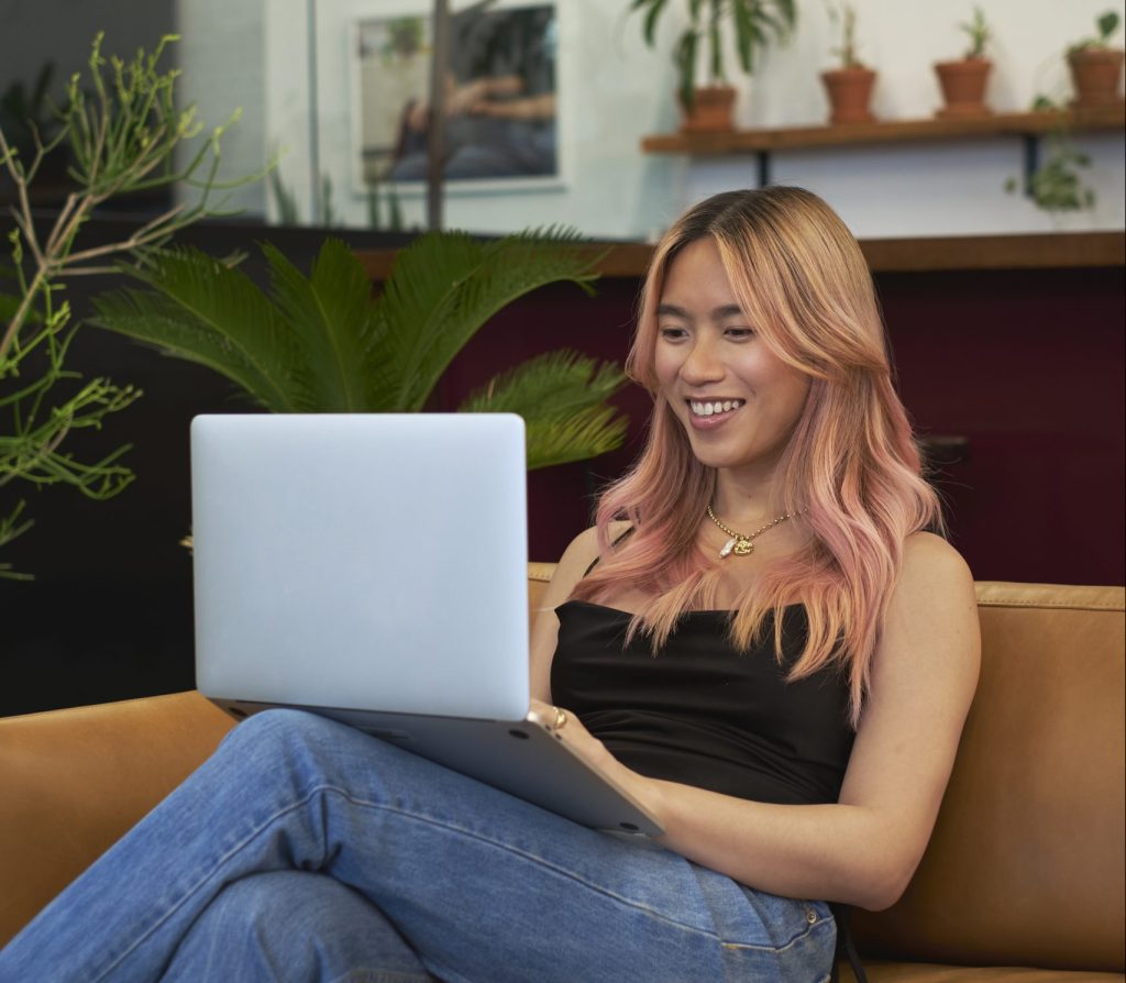A-transfeminine-person-smiling-and-using-a-laptop