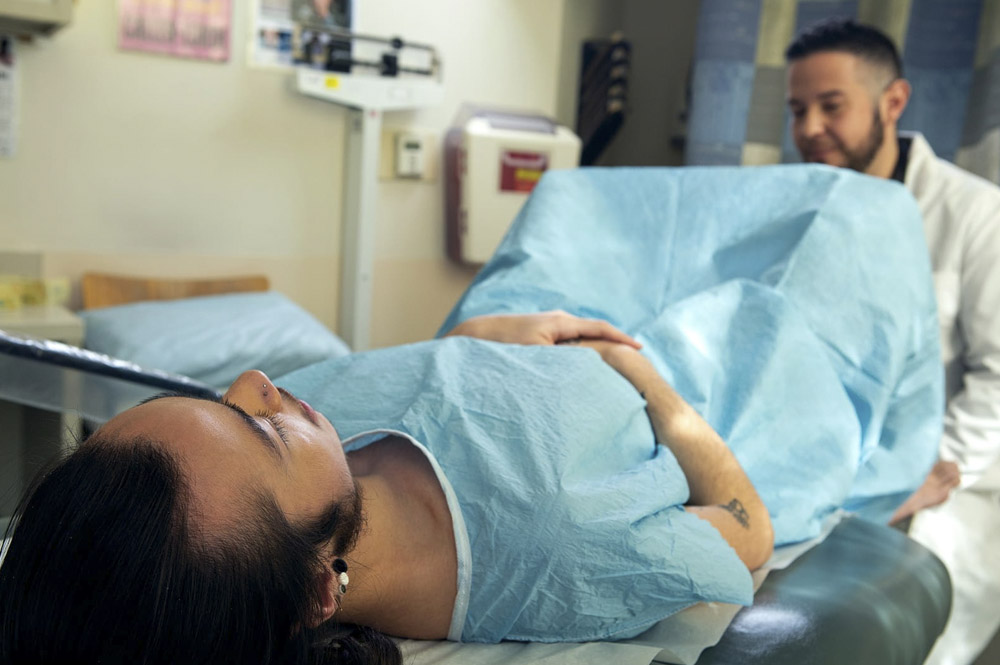 Foto onderzoek ziekenhuis met iemand in blauw gewaad op de ligstoel bij de dokter