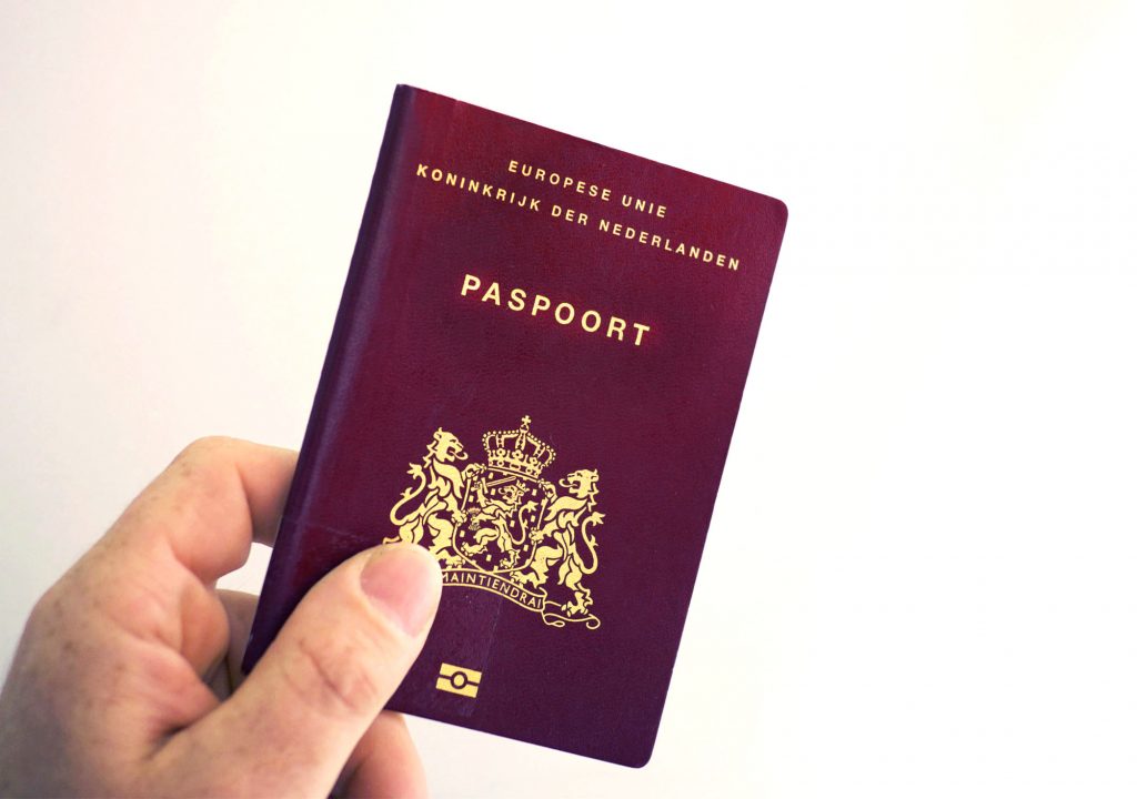 Foto van een Nederlands paspoort die vastgehouden word door een hand