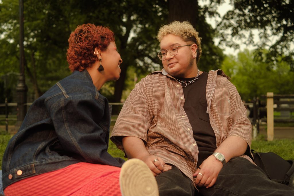 foto van 2 trans personen die naar elkaar kijken in een park