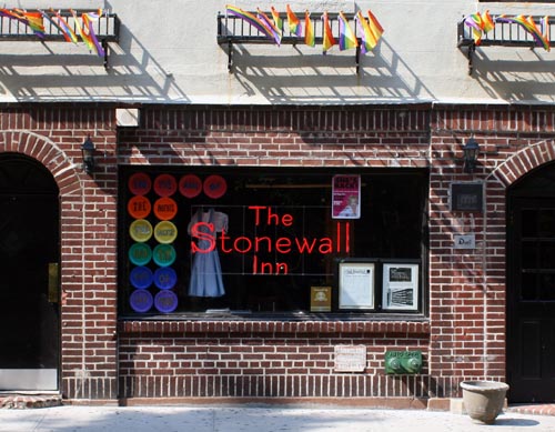 Foto van de gevel van The Stonewall Inn met allemaal kleine regenboogvlaggetjes aan de gevel.