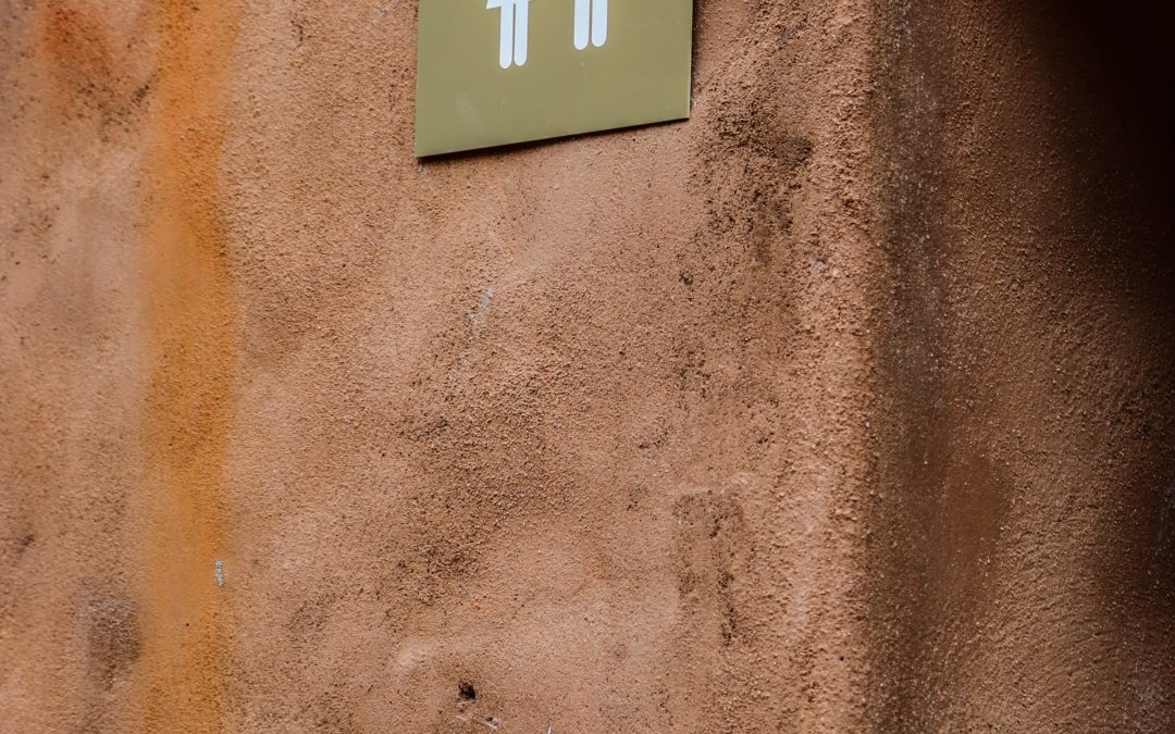 Foto van een aardekleur muur met toiletsign (man/vrouw afbeelding)