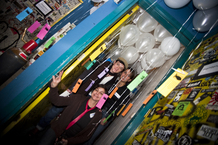 Transgender gedenkdag 2009, foto van drie personen in een deuropening van een gang. De gang hangt vol met ballonnen.