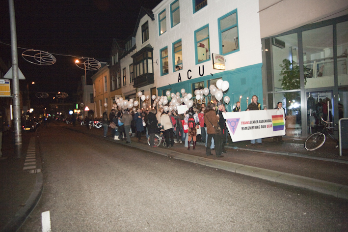 Transgender gedenkdag 2009, foto van een groep mensen die over straat lopen. De voorste personen dragen een hele grote banner met daarop de tekst: transgender gedenkdag, remembering our dead.
