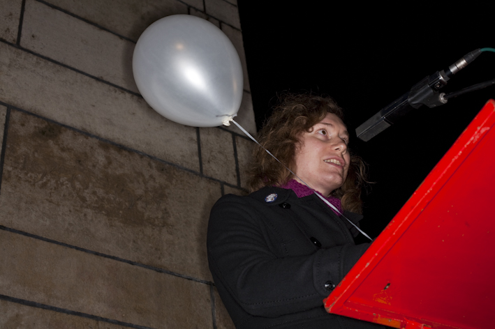Transgender gedenkdag 2009, foto van een persoon die voor een microfoon staat en mensen toespreekt.