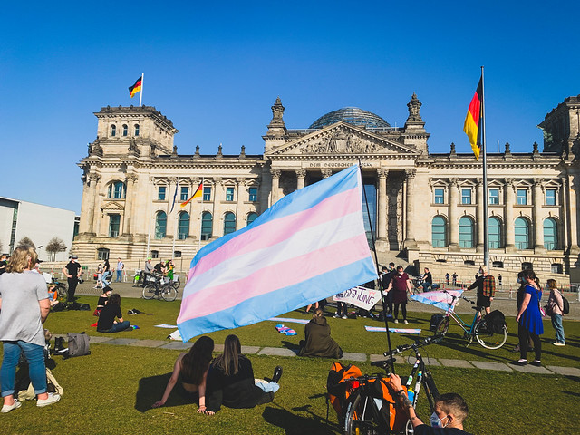 Foto van een demonstratie voor de Bundestag in Duitsland. Voorop de foto staat een grote transgendervlag