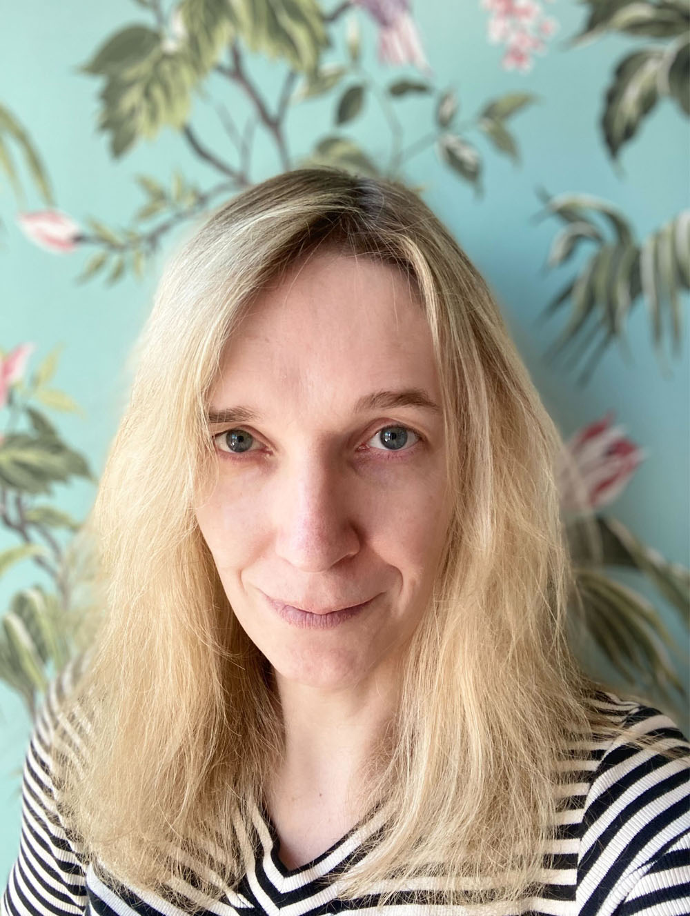 Portret van Tessa voor een turqoise muur met planten en bloemen erop