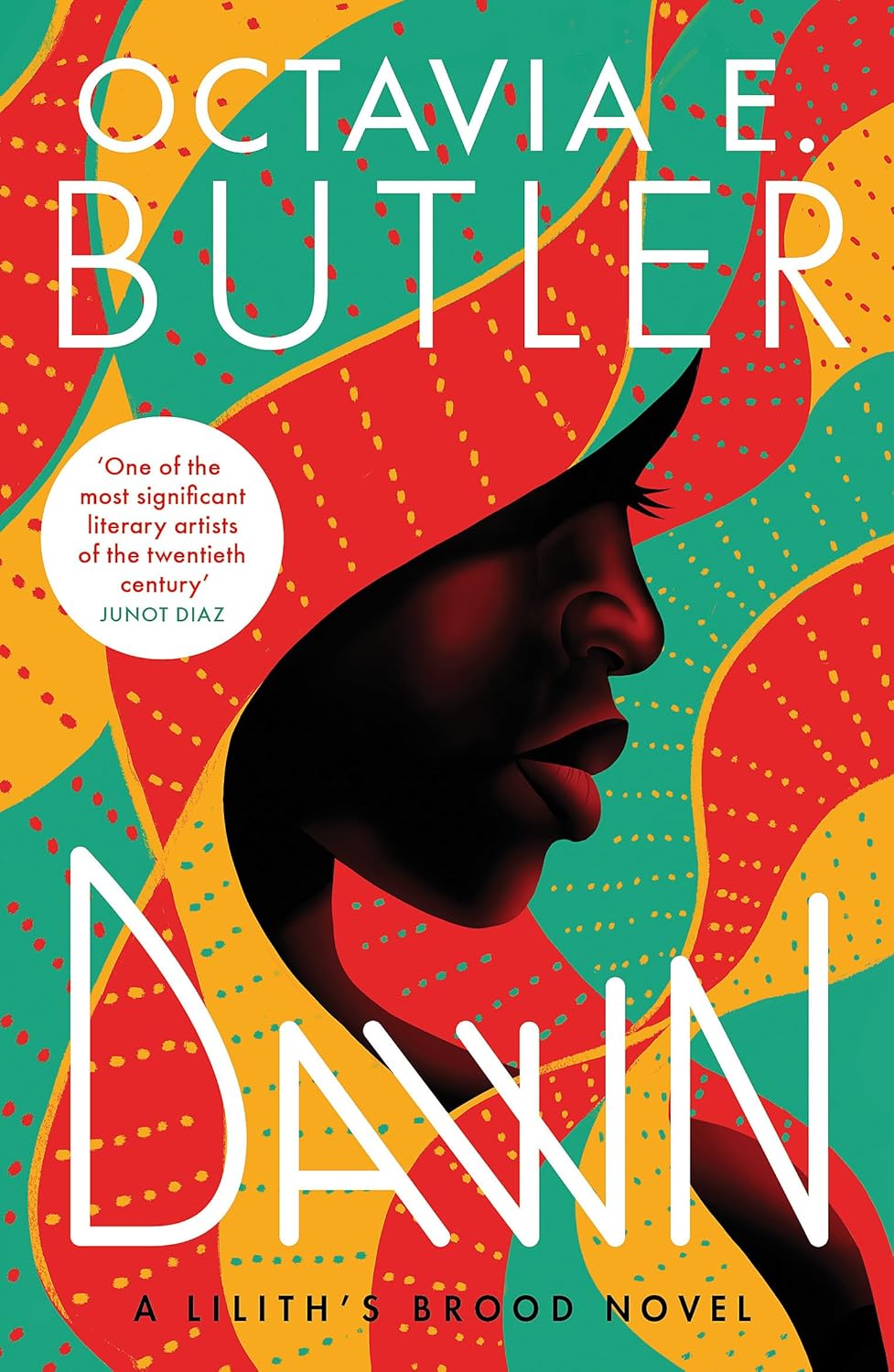 Boekcover van Dawn van Octavia E. Butler. Centraal staat een kleurrijke illustratie van een gezicht in profiel, met rode, oranje en groene grafische patronen. De titel “DAWN” staat in grote witte letters, en bovenaan staat de naam van de auteur. In een wit cirkelvormig tekstblok staat een quote van Junot Diaz over de literaire betekenis van Butler.