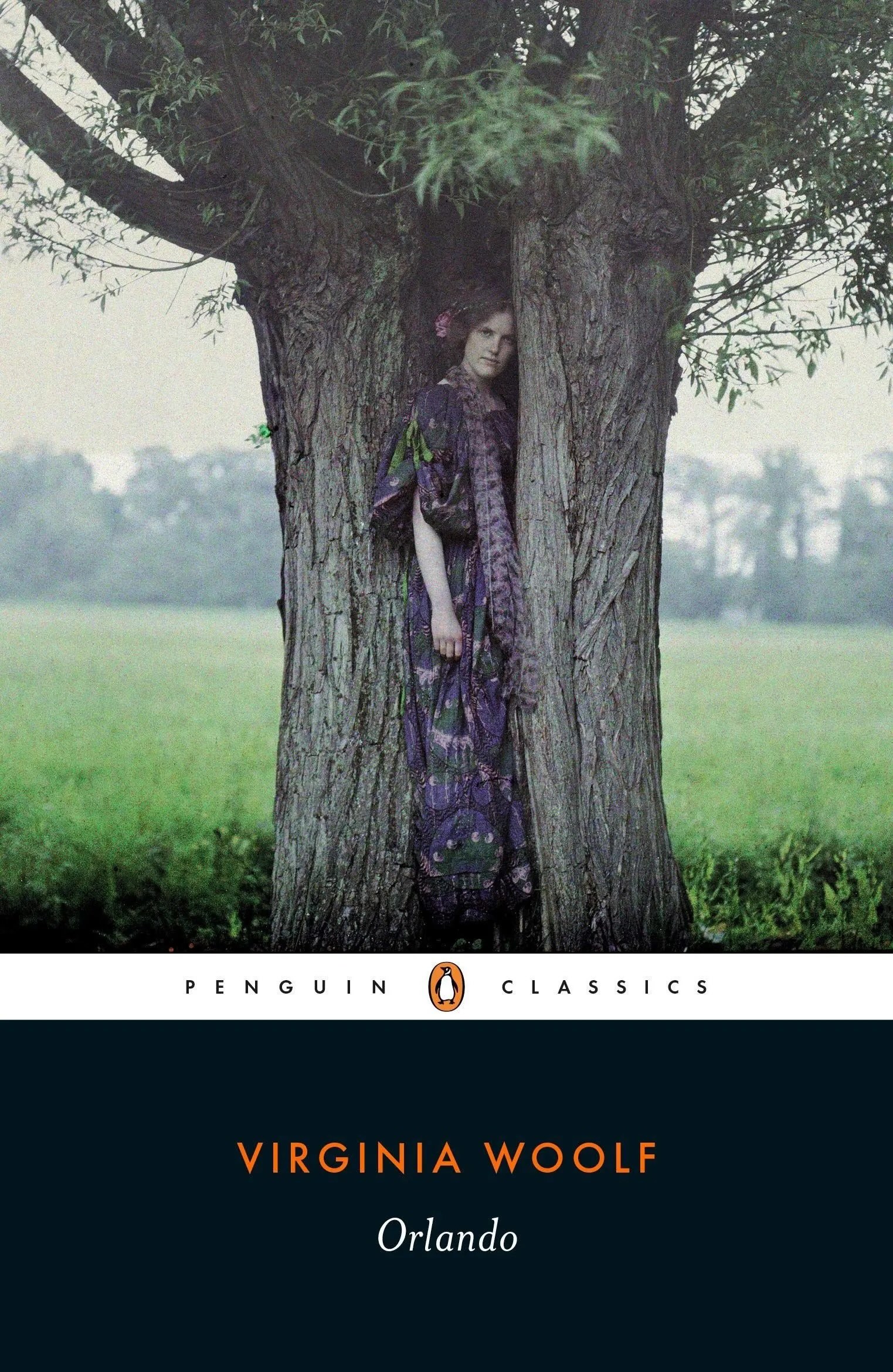 Omslag van het boek Orlando van Virginia Woolf (Penguin Classics-editie). De cover toont een persoon in een paars gewaad die tussen de stammen van een boom staat. De setting is een groen veld met bomen in de verte. De onderzijde van de cover is donkerblauw met het Penguin Classics-logo, de naam van de auteur en de titel.