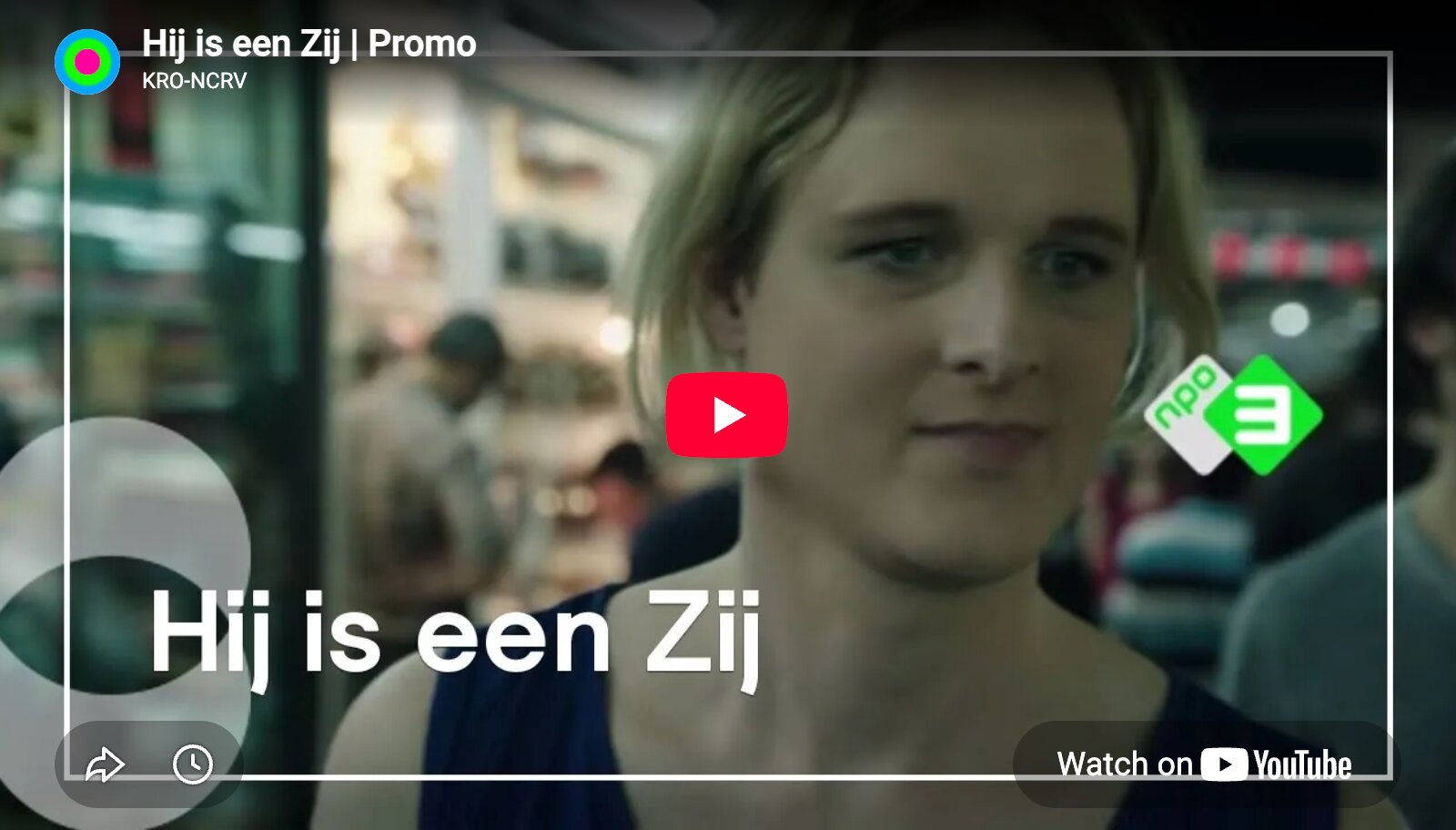 Videominiatuur van een promo: close-up van een persoon met kort blond haar in een winkel. Linksonder grote tekst Hij is een Zij. Midden een rode YouTube-afspeelknop. Boven links KRO-NCRV, rechts NPO3-logo.